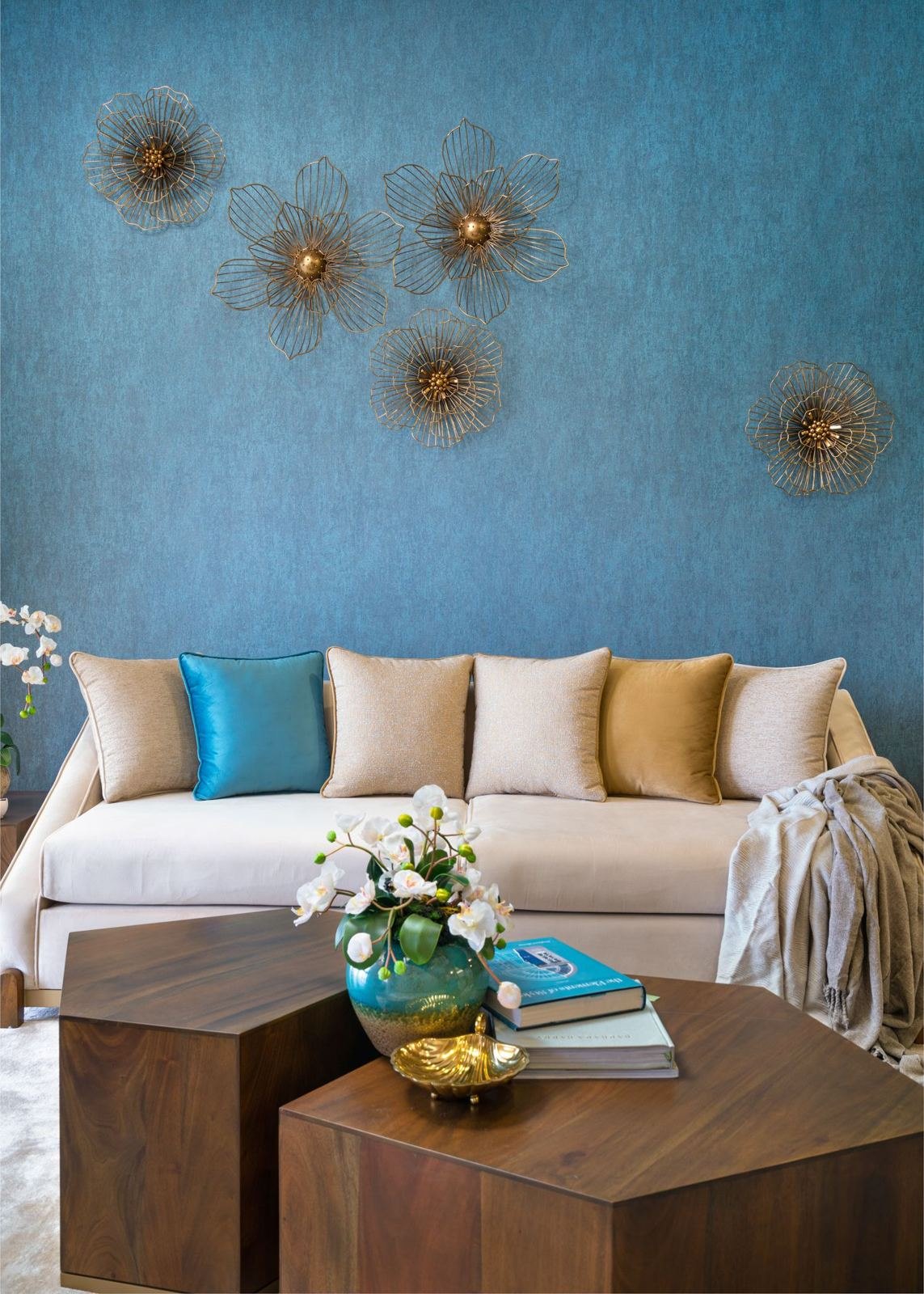 Faceted walnut occasional tables against a teal wall
