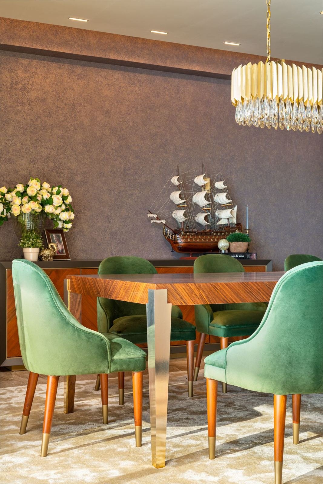 Dining room with deep-green velvet chairs and a crystal pendant